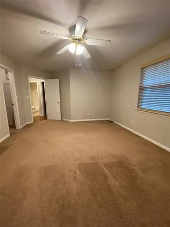 an empty room with chandelier fan and windows