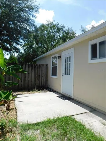 a backyard of a house with large trees and wooden fence