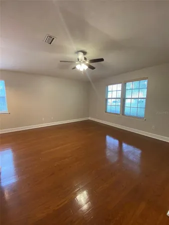 a view of an empty room with chandelier fan and a window