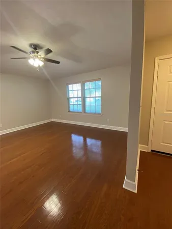 an empty room with wooden floor fan and windows