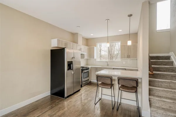 a kitchen with stainless steel appliances granite countertop a refrigerator a stove a sink dishwasher and white cabinets with wooden floor
