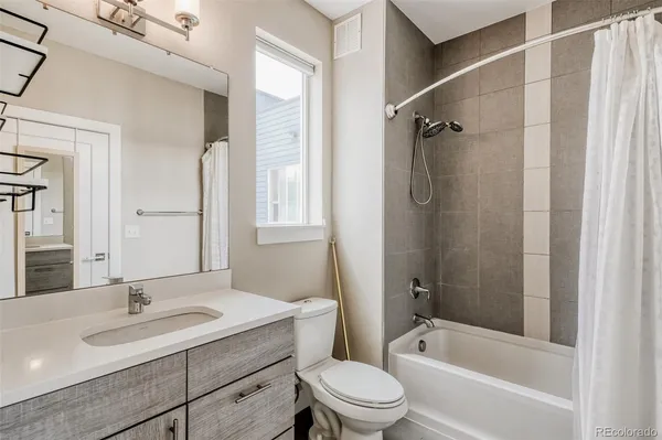 a bathroom with a granite countertop sink a toilet and shower