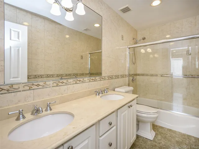 a bathroom with a granite countertop sink a toilet and shower