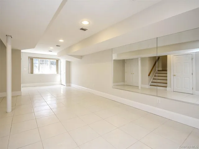 a view of an empty room with stairs and a window