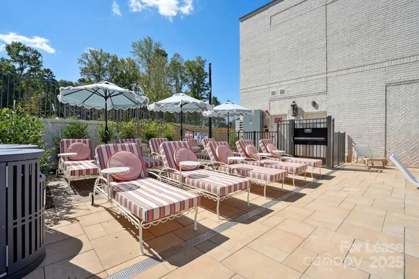 a view of a patio with a dining table and chairs under an umbrella with a barbeque