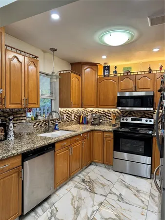 a kitchen with stainless steel appliances granite countertop a sink and a stove