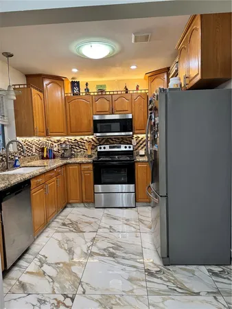 a kitchen with stainless steel appliances granite countertop a stove a sink and a refrigerator