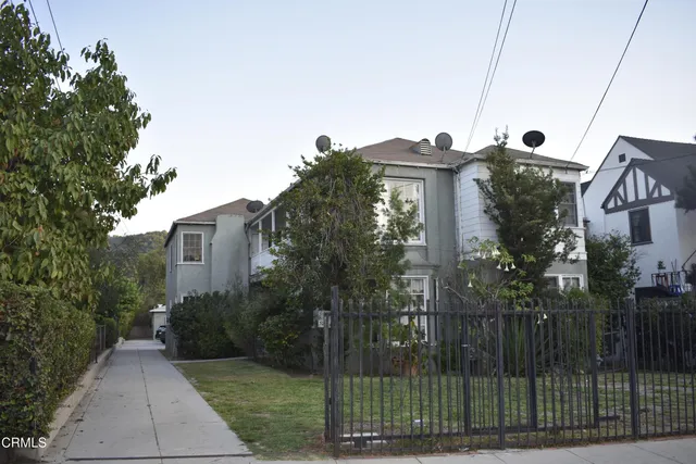 a view of a house with a small yard and wooden fence