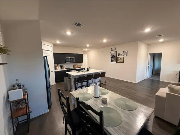 a room with a table chairs and a refrigerator