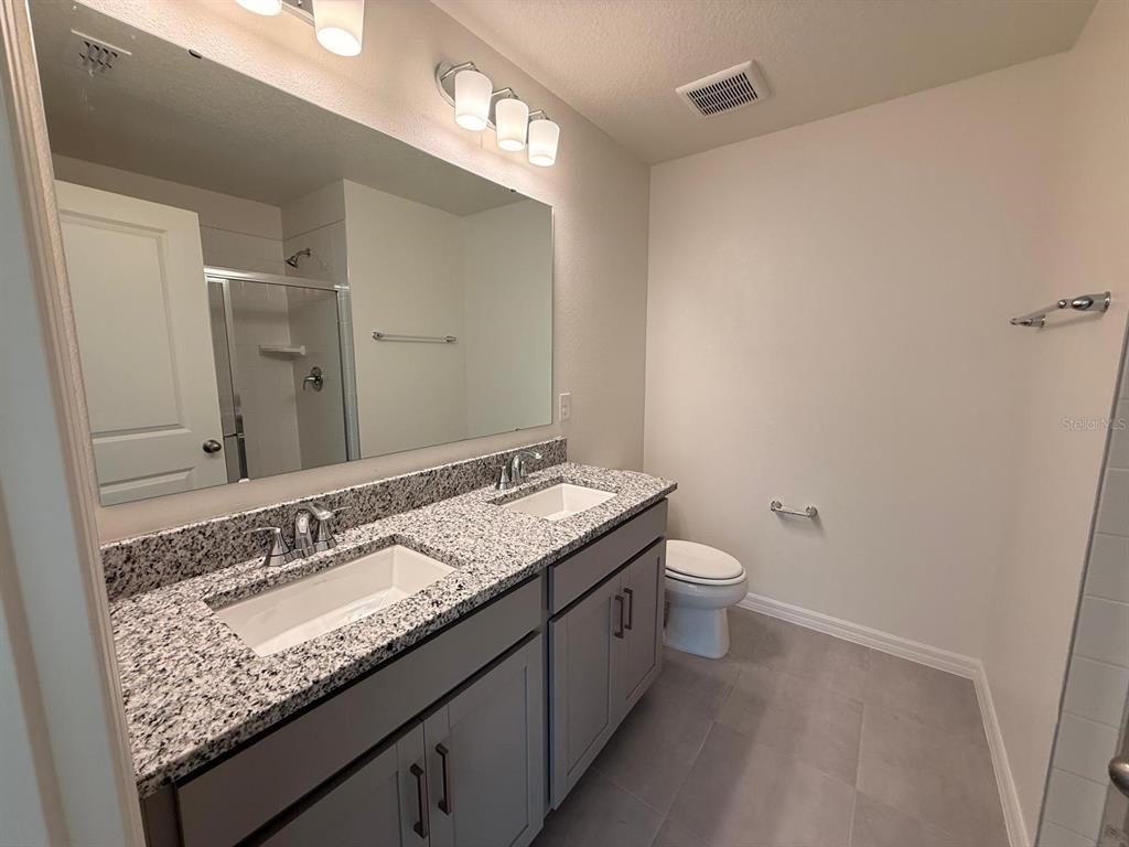 16607 Luminary Loop Clermont, FL 34714 - Photo 11 of 18 a bathroom with a granite countertop sink and a mirror