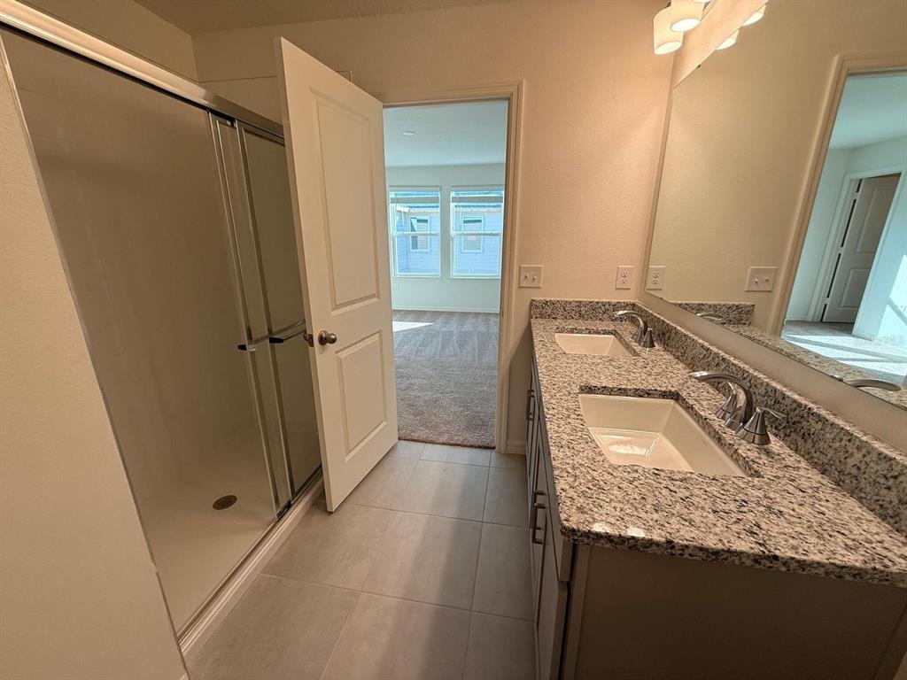 16607 Luminary Loop Clermont, FL 34714 - Photo 12 of 18 a bathroom with a granite countertop sink and a mirror