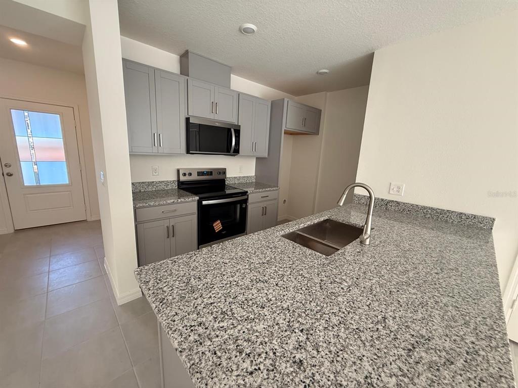 16607 Luminary Loop Clermont, FL 34714 - Photo 2 of 18 a kitchen with stainless steel appliances granite countertop a sink stove and refrigerator