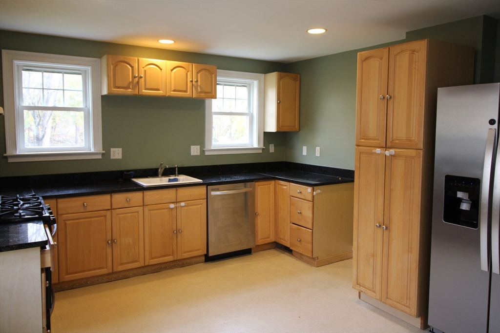 4 Wilson Street, Unit LEFT Billerica, MA 01862 - Photo 2 of 29 a kitchen with granite countertop white cabinets white stainless steel appliances a sink and a window