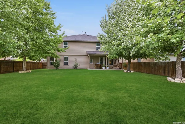 a view of yard with grass and trees in the background
