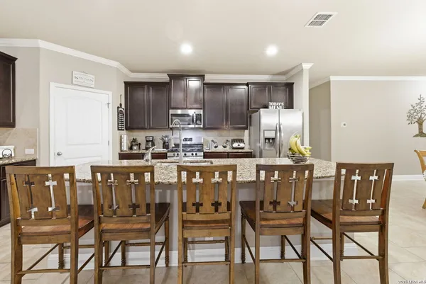 a kitchen with a dining table chairs and refrigerator