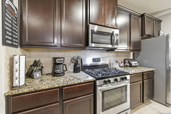 a kitchen with granite countertop stainless steel appliances stove top oven and cabinets