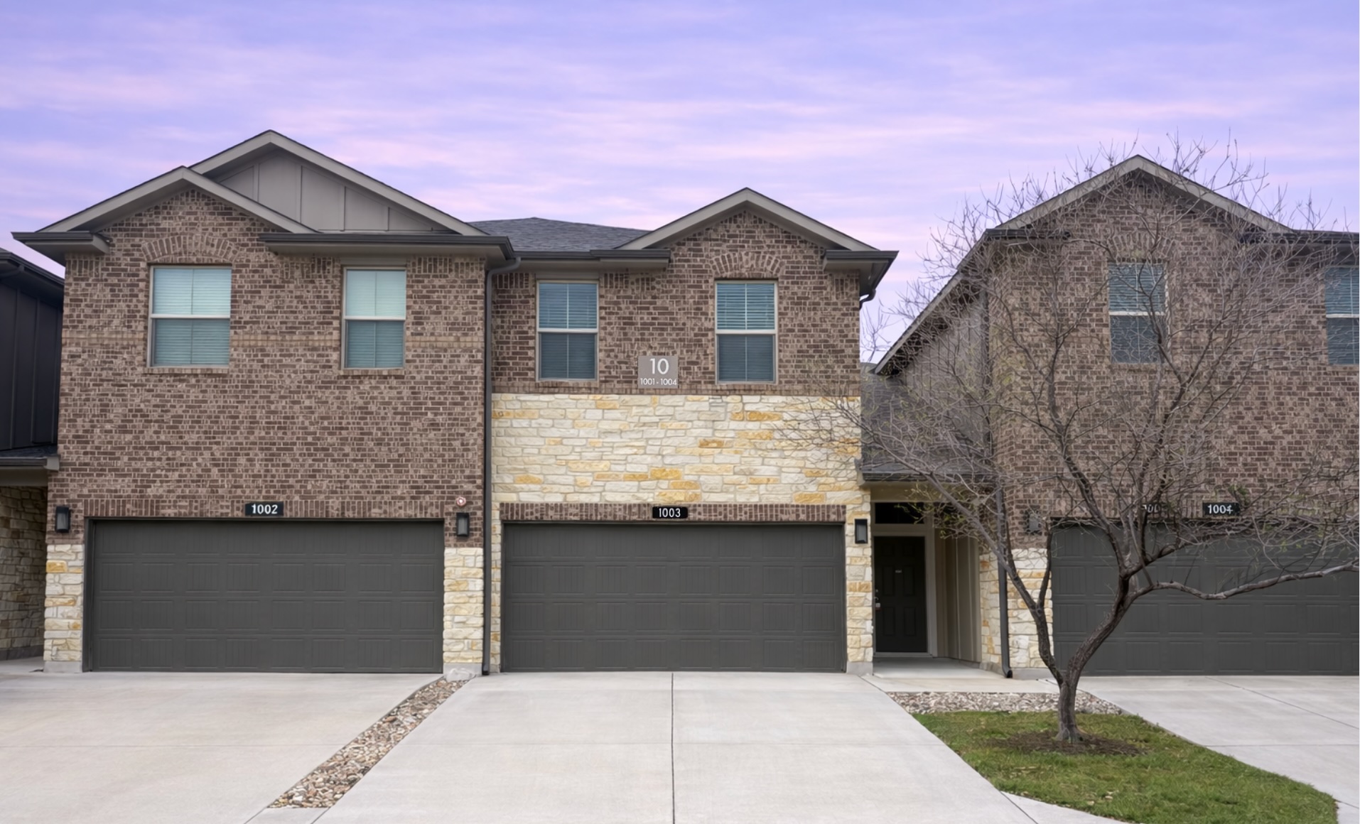 1200 10th Street, Unit 1003 Pflugerville, TX 78660 - Photo 1 of 1 View of front of property featuring board and batten siding, driveway, a garage, and stone siding