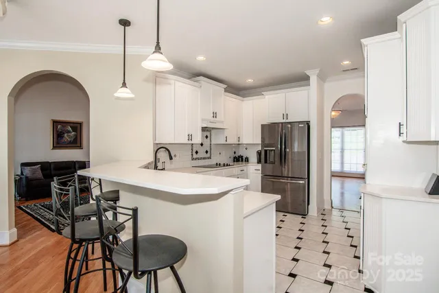 a kitchen with stainless steel appliances a refrigerator a sink a stove a table and chairs
