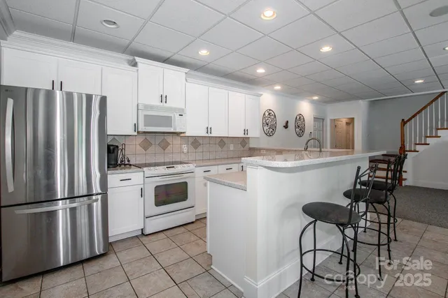 a kitchen with granite countertop a refrigerator oven a sink dishwasher and white cabinets with wooden floor