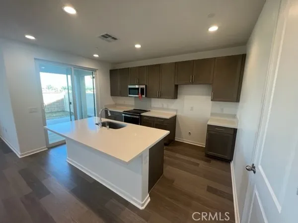 a large kitchen with stainless steel appliances a large counter top a stove a sink and a refrigerator
