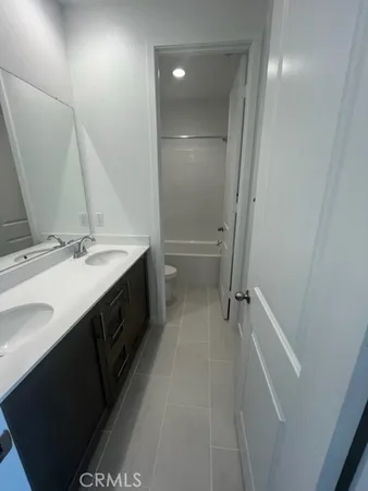 a bathroom with a double vanity sink a toilet and a mirror