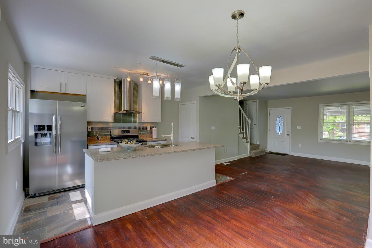 6023 Falkirk Road Baltimore, MD 21239 - Photo 7 of 20 a kitchen with stainless steel appliances granite countertop a refrigerator a sink dishwasher a stove and a dining table with wooden floor
