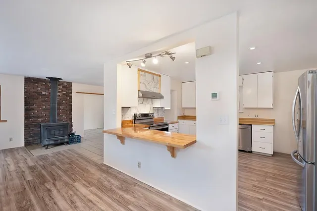 a open kitchen with stainless steel appliances a refrigerator and a stove top oven