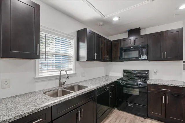 a kitchen with granite countertop stainless steel appliances a sink stove and cabinets