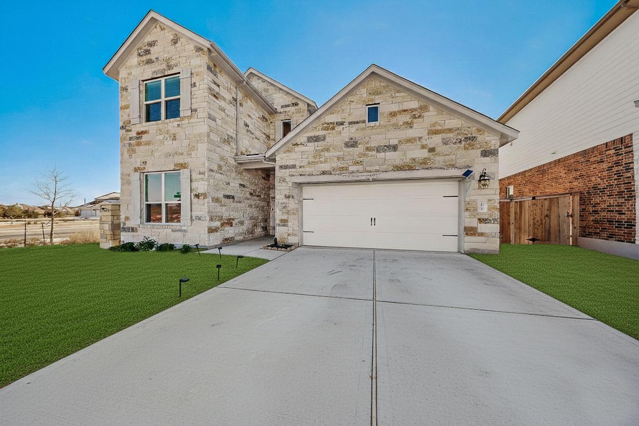 View of front of house with stone siding, concrete driveway, and a garage
