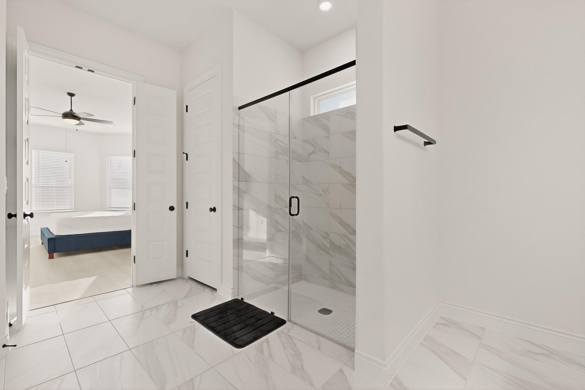 2121 Lolo Lane Leander, TX 78641 - Photo 14 of 26 Bathroom featuring ensuite bath, a marble finish shower, light marble finish flooring, and a ceiling fan