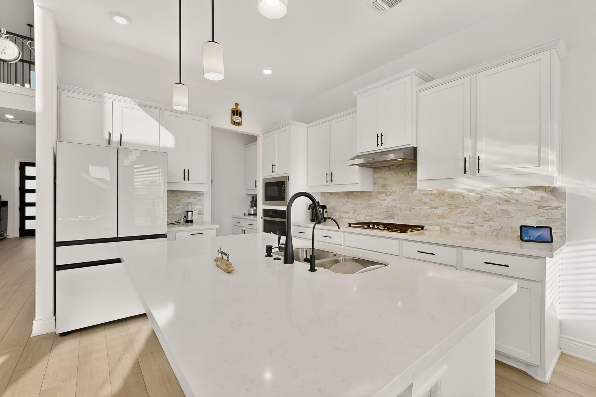 2121 Lolo Lane Leander, TX 78641 - Photo 7 of 26 Kitchen with freestanding refrigerator, light wood-style flooring, white cabinets, tasteful backsplash, and recessed lighting