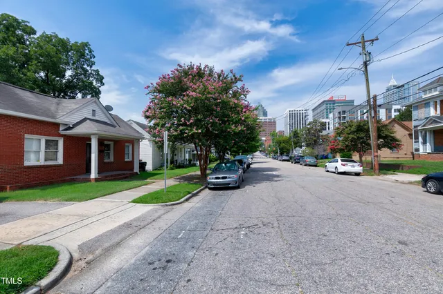 a view of a brick house with a big yard and large trees