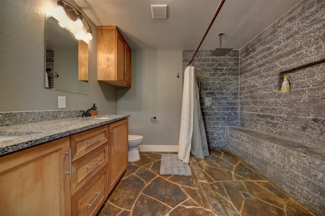a bathroom with a granite countertop sink toilet and shower