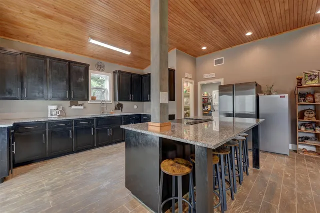 a kitchen with stainless steel appliances kitchen island granite countertop a table chairs in it and wooden floors