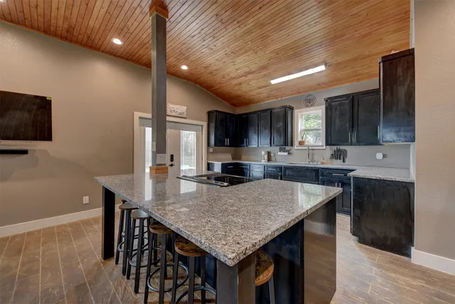 a kitchen with granite countertop kitchen island stainless steel appliances sink microwave and cabinets