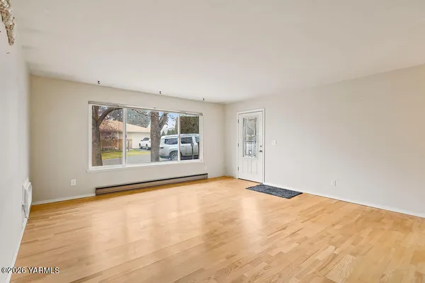 a view of an empty room with a window and wooden floor