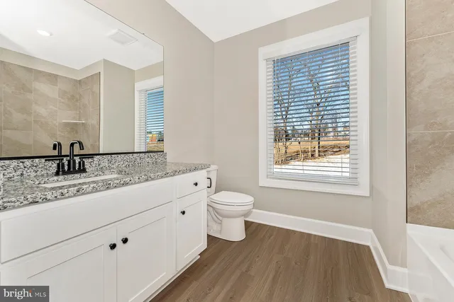 a bathroom with a granite countertop sink toilet a large mirror and shower