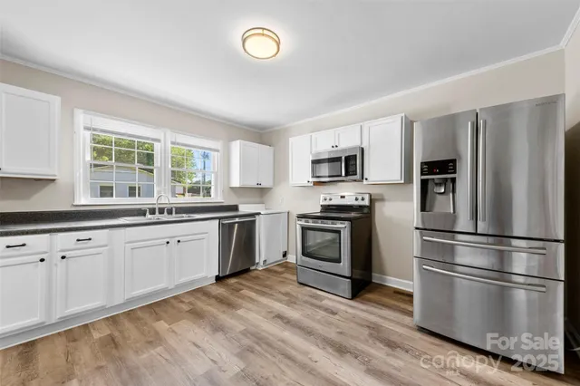 a kitchen with granite countertop stainless steel appliances a sink cabinets and a window