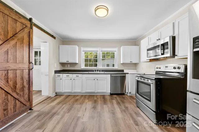 a kitchen with stainless steel appliances granite countertop a stove a sink dishwasher and a refrigerator with wooden floor