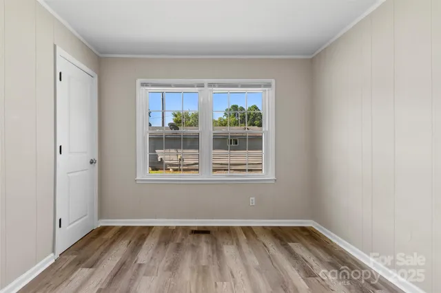 a view of an empty room with a window and wooden floor
