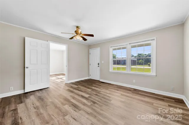 a view of an empty room with window and wooden floor