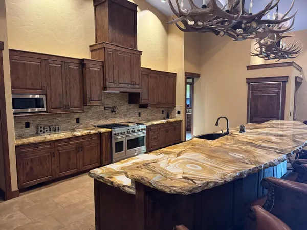 a kitchen with kitchen island granite countertop wooden cabinets a stove top oven a sink and dishwasher