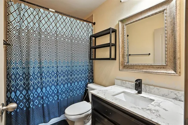a bathroom with a granite countertop toilet sink and mirror