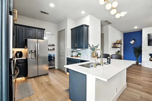 a kitchen with stainless steel appliances kitchen island granite countertop a sink refrigerator and cabinets
