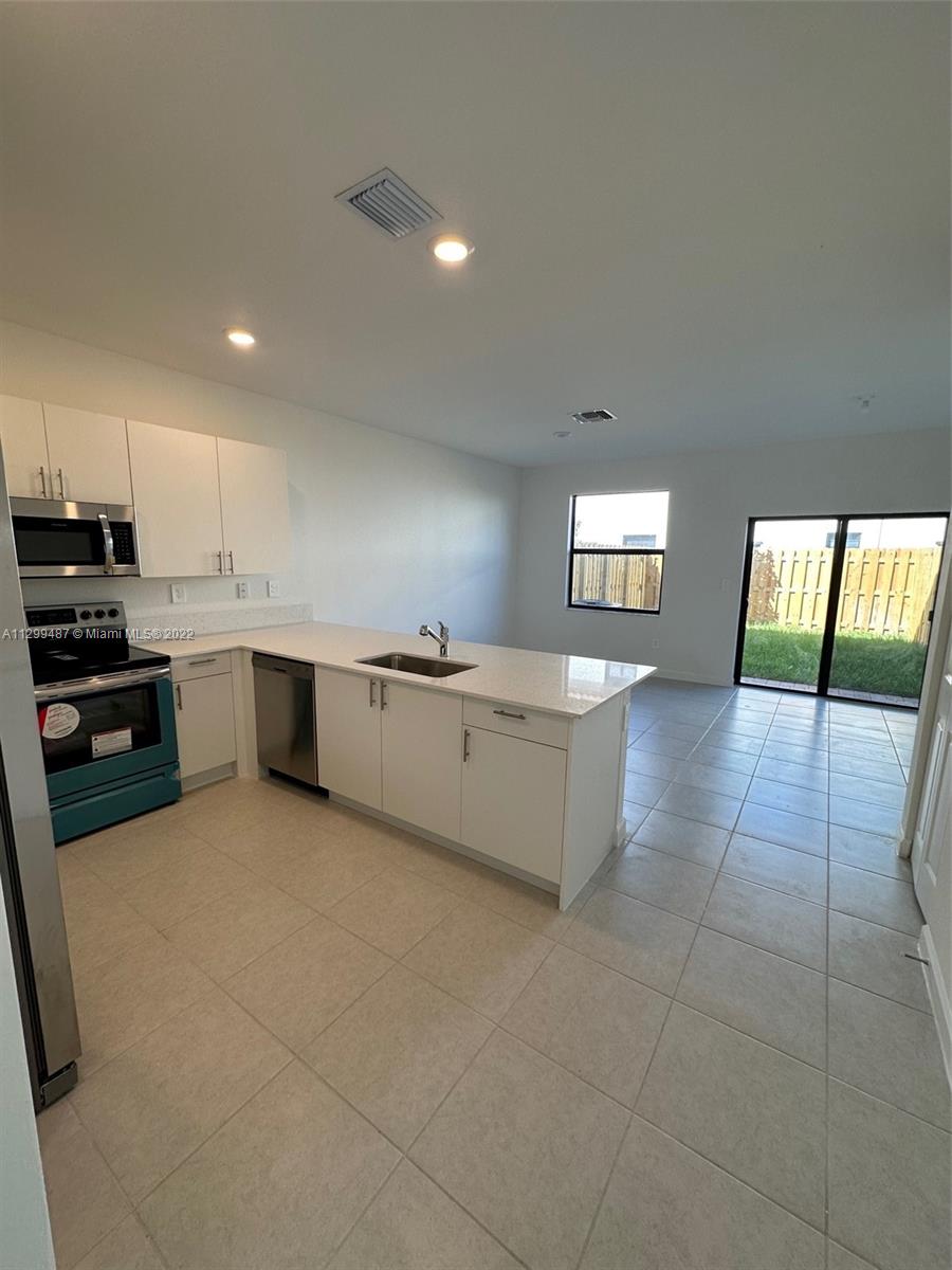 11863 Southwest 247th Terrace, Unit 11863 Homestead, FL 33032 - Photo 5 of 10 a large kitchen with a stove a sink and a microwave