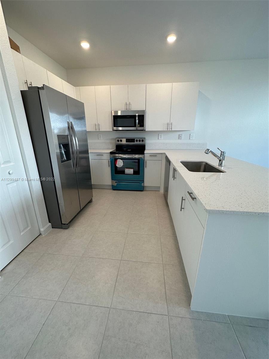11863 Southwest 247th Terrace, Unit 11863 Homestead, FL 33032 - Photo 7 of 10 a large kitchen with stainless steel appliances granite countertop a stove a sink and a refrigerator