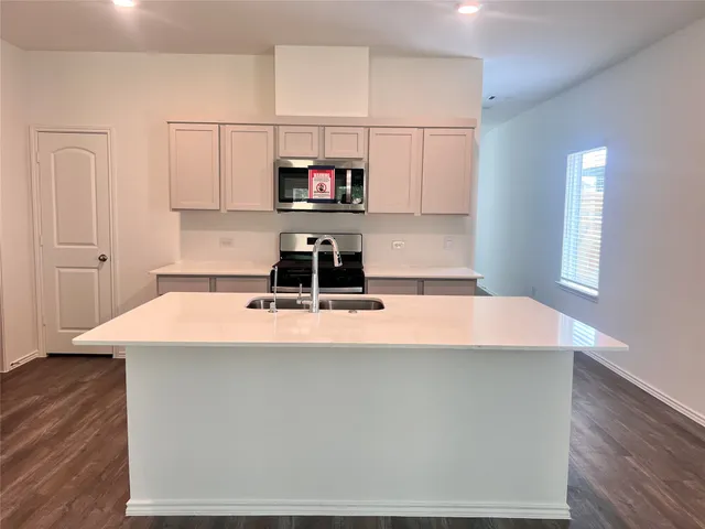 a kitchen with kitchen island a sink a stove a refrigerator and white cabinets