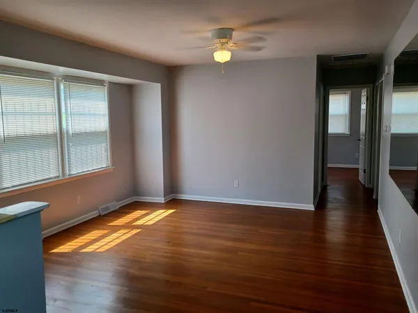 a view of empty room with wooden floor and fan