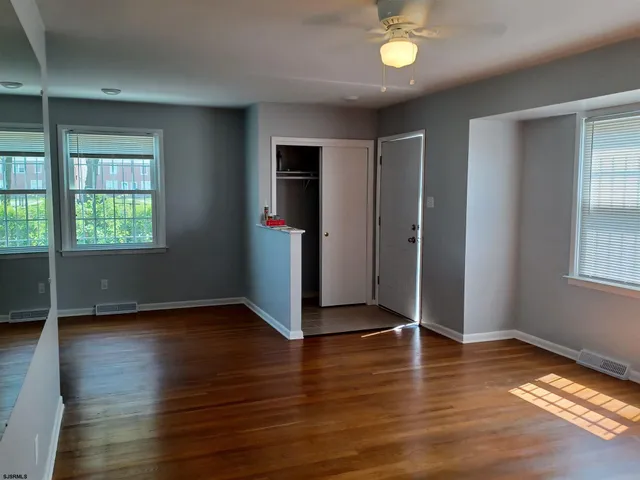 an empty room with wooden floor and windows