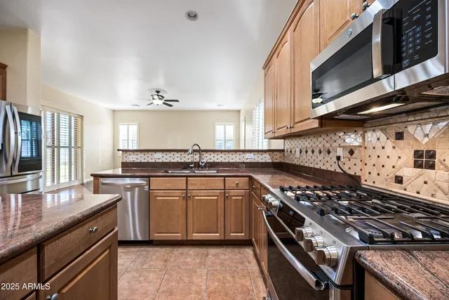 a kitchen with stainless steel appliances granite countertop a stove a sink dishwasher and cabinets with wooden floor